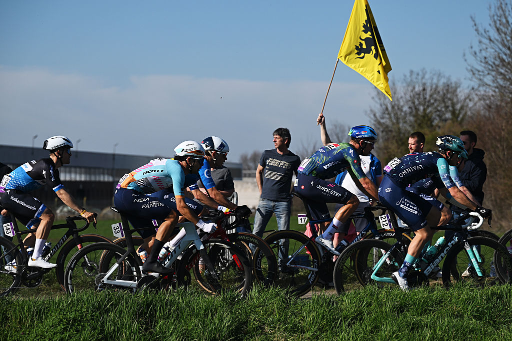 Cyclists race next to a grassy bank