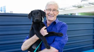 Paul O'Grady cuddles a black labrador at Battersea Dogs & Cats Home