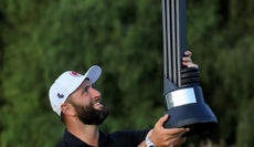 Jon Rahm holds a LIV trophy in the air