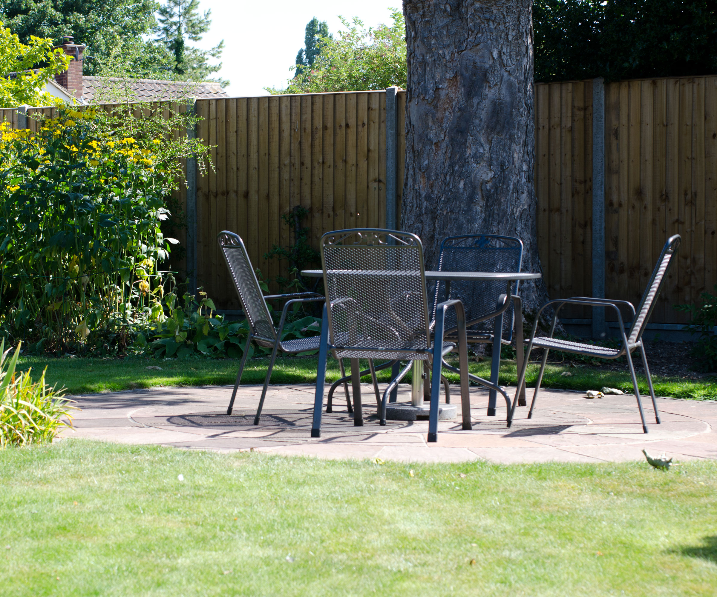 simple circular patio with garden furniture, lawn and shrubs