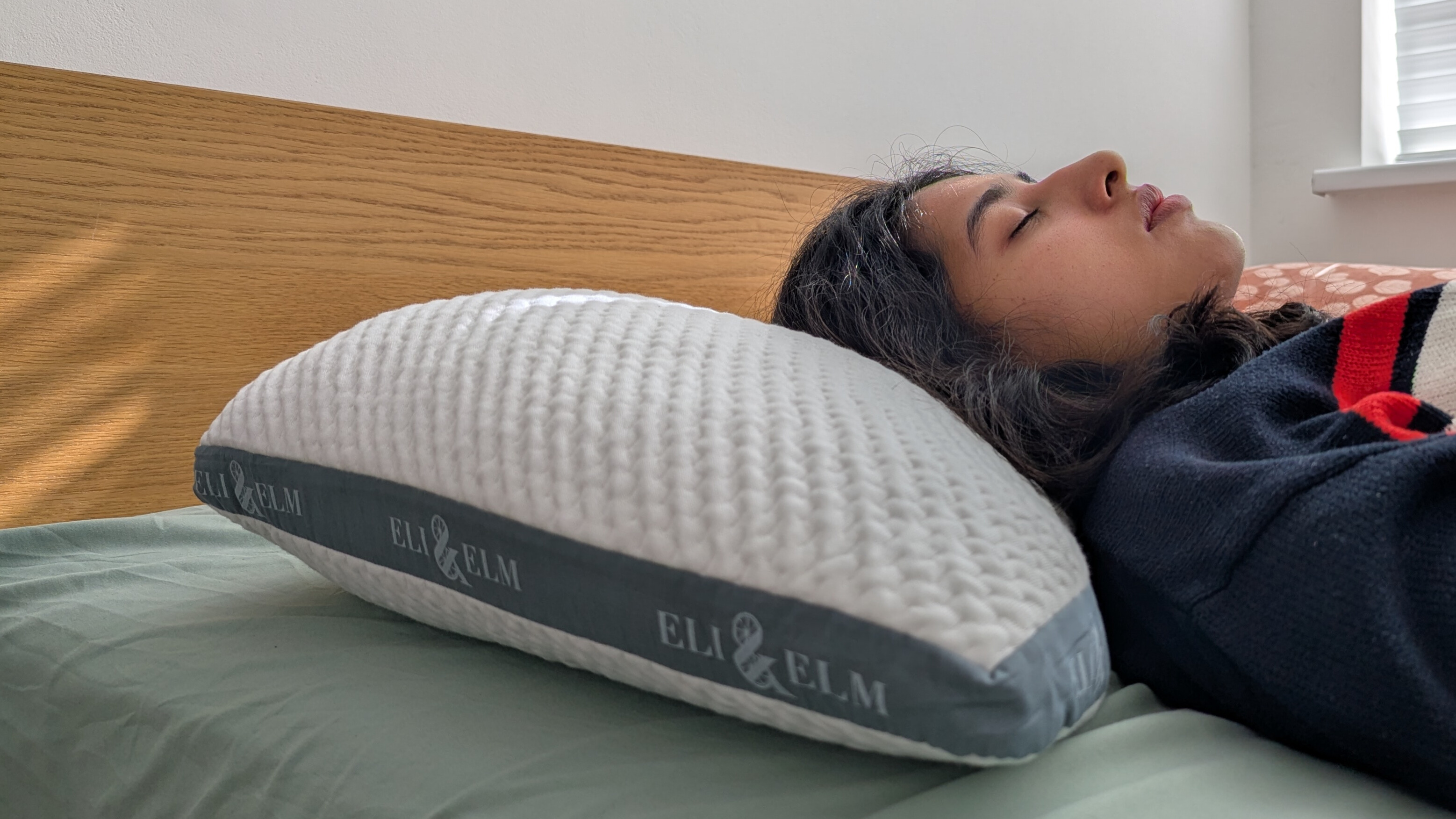 A close-up shot of a woman sleeping on her back on the Eli and Elm Side Sleeper Pillow in a brightly lit room