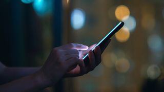 Close up of woman&#039;s hand using Android smartphone in the dark