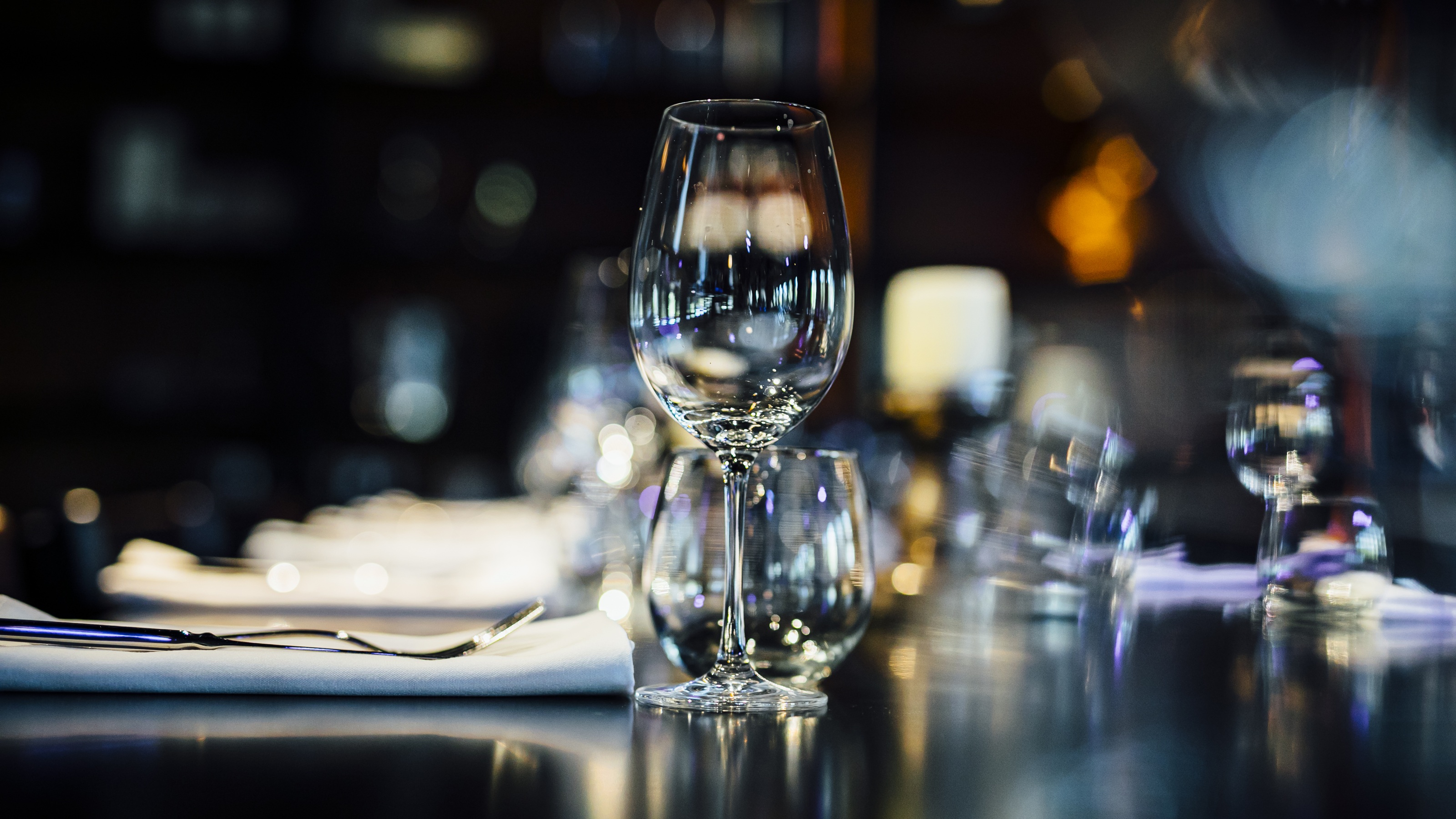 Luxury table settings for fine dining with glassware and a blurred background.