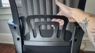 A hand bending the lumbar support on a cheap office chair