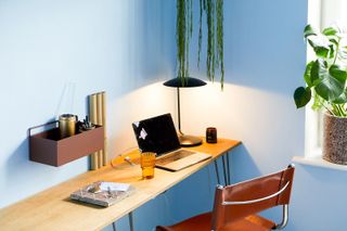 A home office with blue walls, a laptop, and a candle