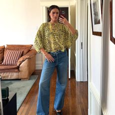 Caitlin Miyako wearing wide-leg denim jean, green and black animal print blouse, and black ballet flats. 