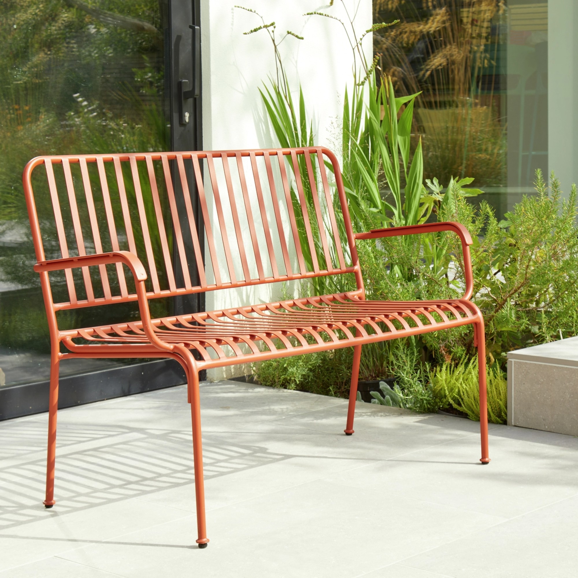 Habitat Indu 2 Seater Metal Garden Bench in Red on a sunny patio