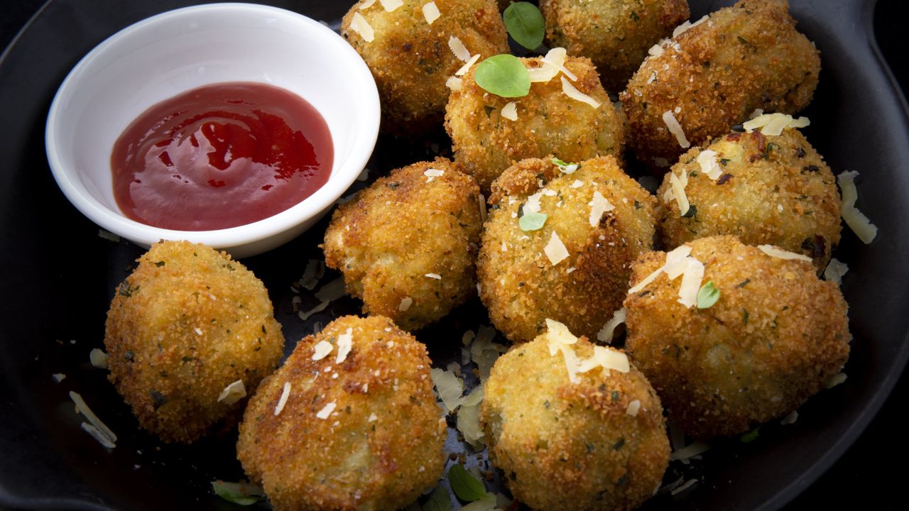 Plate of arancini rice balls with ketchup dipping sauce on the side