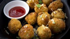 Plate of arancini rice balls with ketchup dipping sauce on the side
