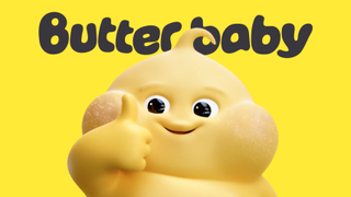 A cheerful, round yellow mascot with rosy cheeks giving a thumbs-up in front of a yellow background with the text "Butter baby" written above.
