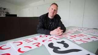 Stephen Banham sitting at a desk with samples of Sans Forgetica