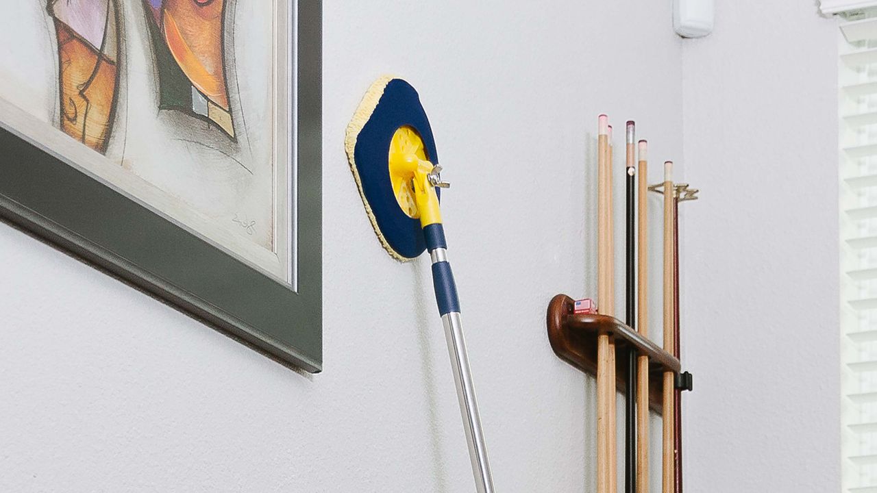 chomp mop being used on a wall with framed artwork and snooker cues