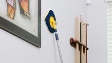 chomp mop being used on a wall with framed artwork and snooker cues