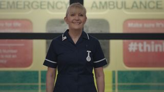 Casualty legend Duffy smiling broadly in her dark navy nurses uniform