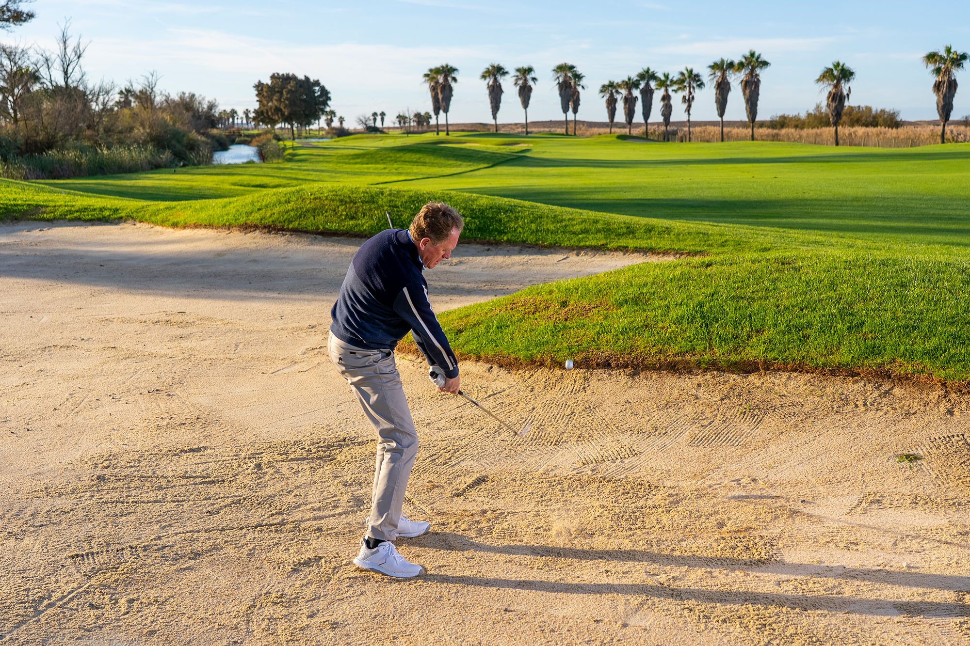 Keith Wood hitting a fairway bunker shot with enough loft to clear the lip but also taking enough club to not be too far back