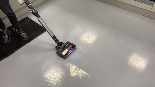 VacTidy Blitz V8 Cordless Vacuum vacuuming up flour on a hard grey floor.