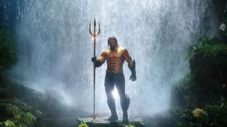 Jason Momoa stands in his Aquaman armor in a waterfall in Aquaman