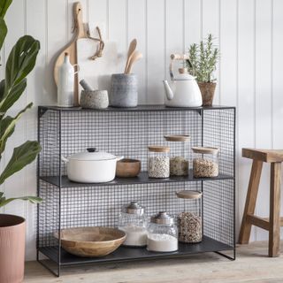 indoor/outdoor kitchen storage wire rack with spice jars, kettle, utensils, chopping boards, plants, wooden bowls