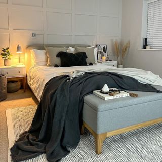 Chic bedroom in tonal grays, with footend storage ottoman with wooden feet and gray upholstery.