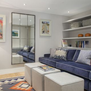 blue sofa in small living room with grid mirror on wall