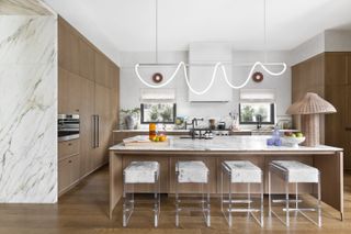 A contemporary wood and marble kitchen with unique modern lighting