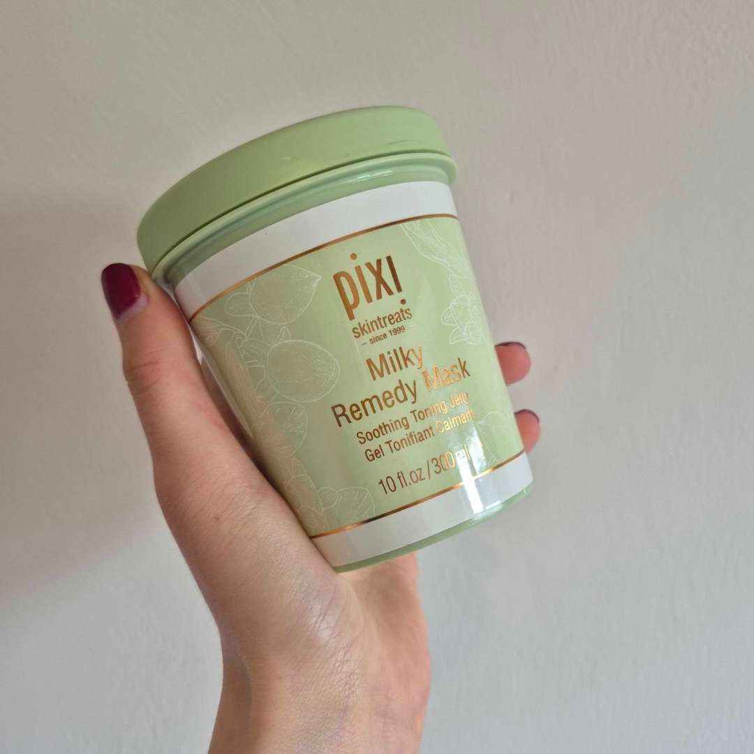 A close-up of Digital Beauty Writer, Naomi Jamieson holding up the Pixi Milky Remedy Mask, in front of a cream wall