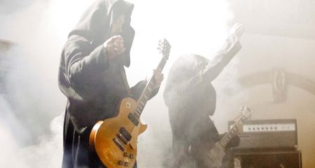 Greg Anderson and Stephen O'Malley of Sunn O))) wear cowls as they perform live in front of banks of high-powered tube amps.