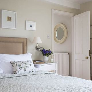 master bedroom with bed with pillows and round mirror on wall