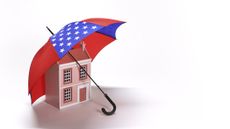 An umbrella evoking the American flag protects a home, symbolizing home insurance and the American dream.