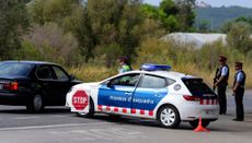 Spanish officers stand next to a police car.