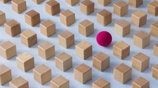 A red ball among several rows of beige blocks.