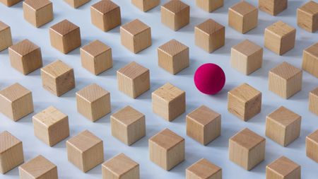 A red ball among several rows of beige blocks.