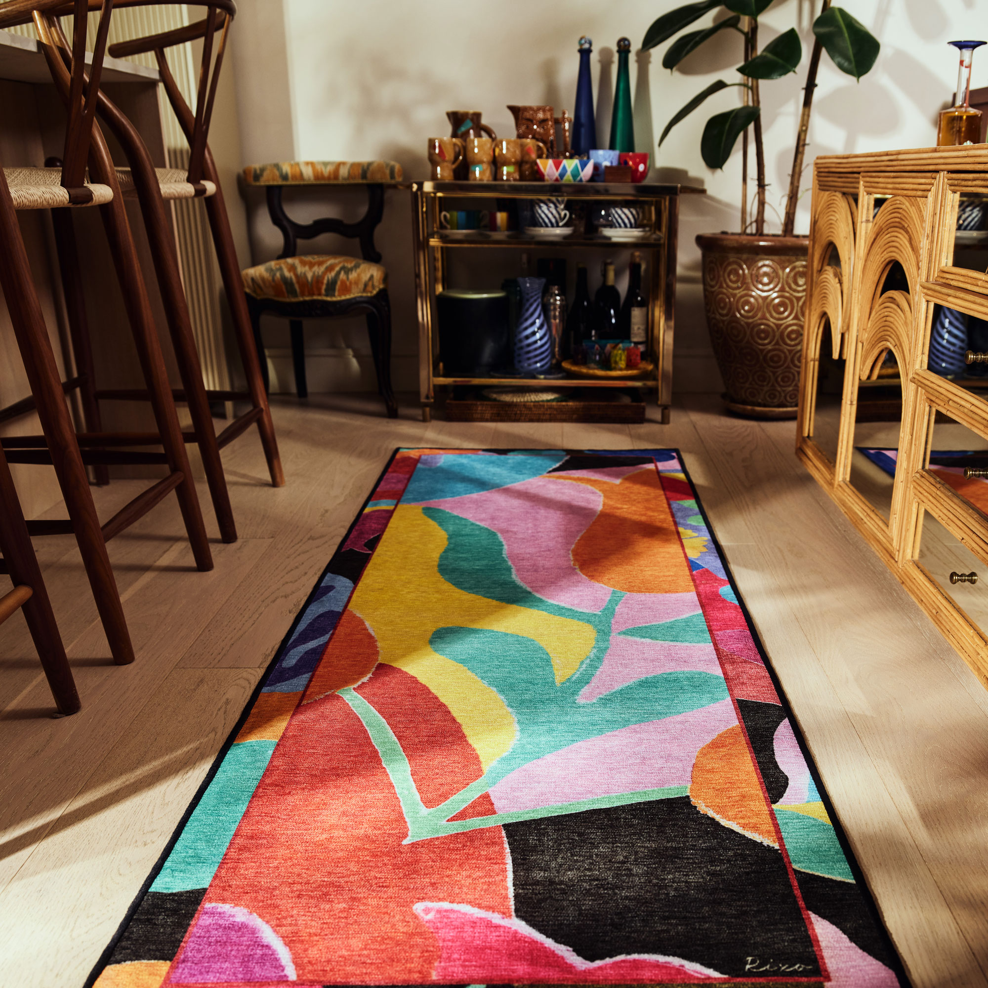 Brightly colour runner rug styled on a wooden floor with drinks cart and vintage sideboard