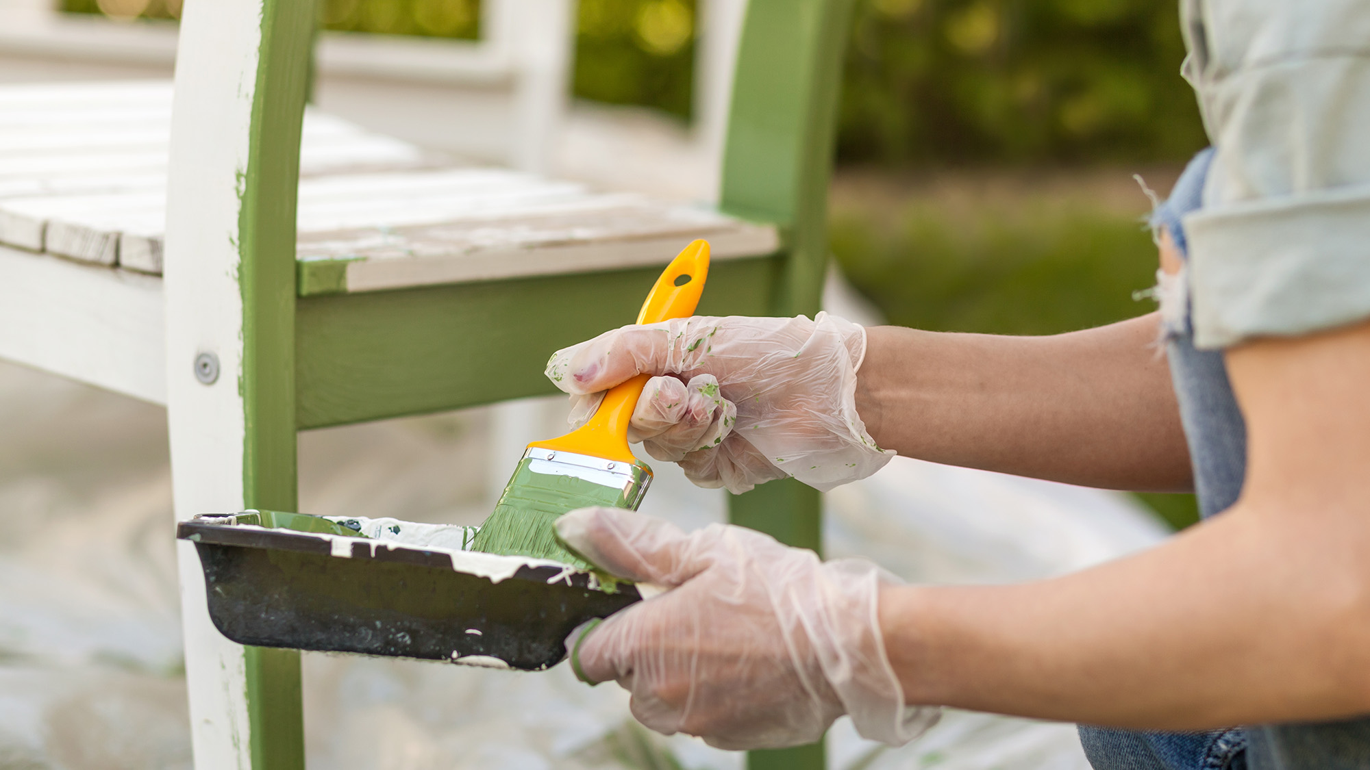 Woman painting garden bench green
