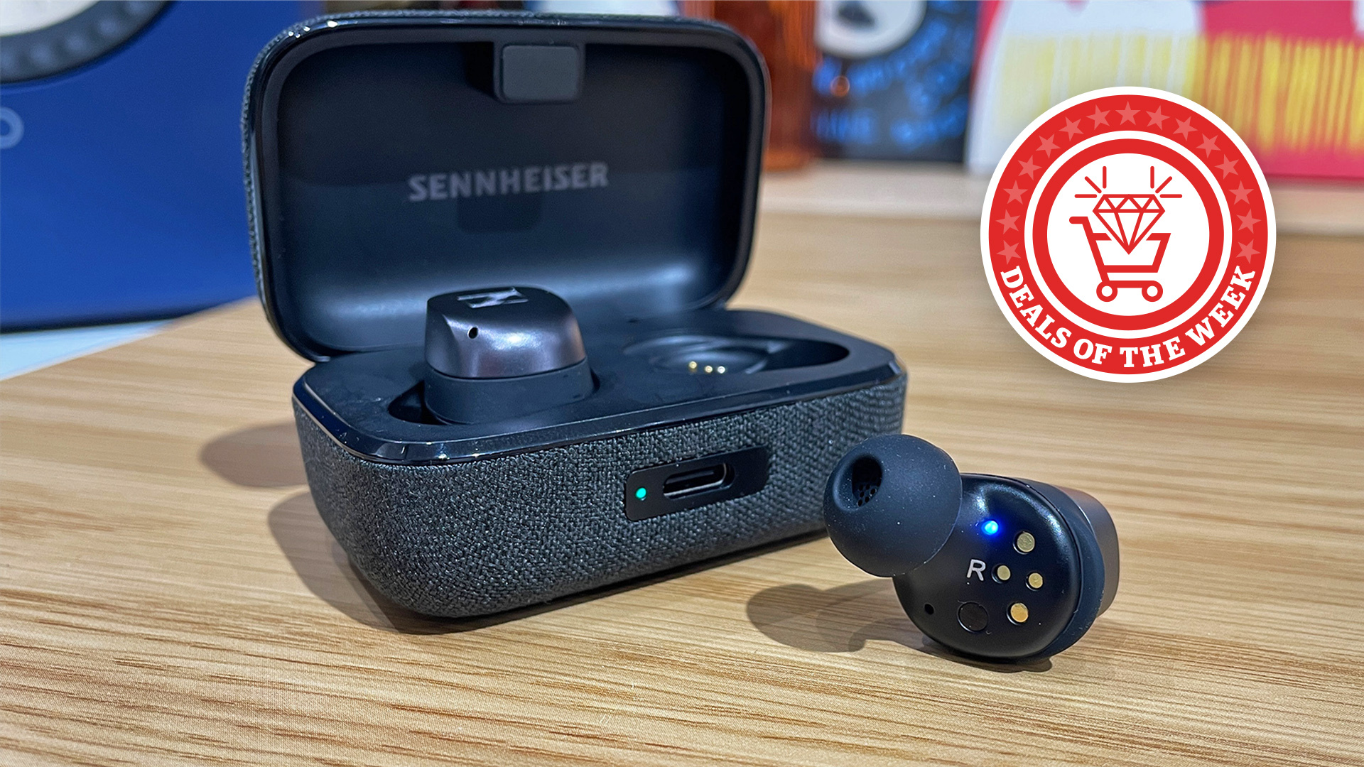 A close-up shot of the Sennheiser Momentum 4 Wireless earbuds, with the case open and one earbud out of the box. The Deals of the Week logo has been added to the image.