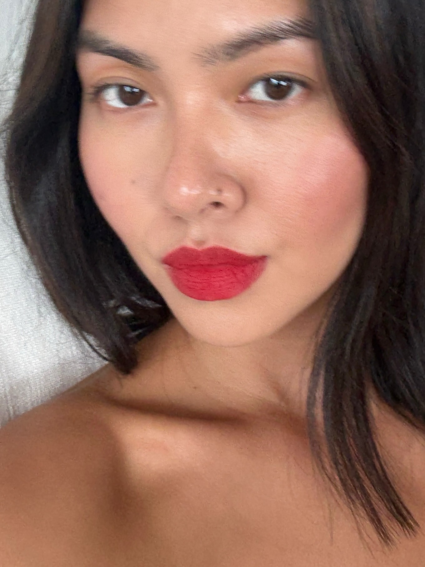 A woman taking a selfie wearing a bold red lip