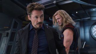 Robert Downey Jr walking past Chris Hemsworth mid-speech in The Avengers.