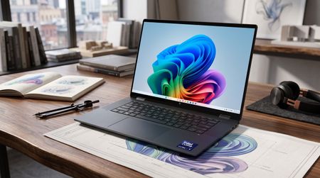 A dark gray laptop with an Intel Core Ultra 7 sticker sits on a wooden desk, displaying a colorful abstract wallpaper on its screen near a notebook.
