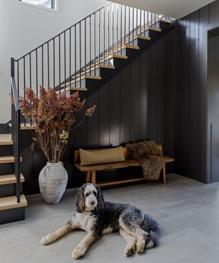 The entrance to a moody boot room, decorated with an antique wooden bench