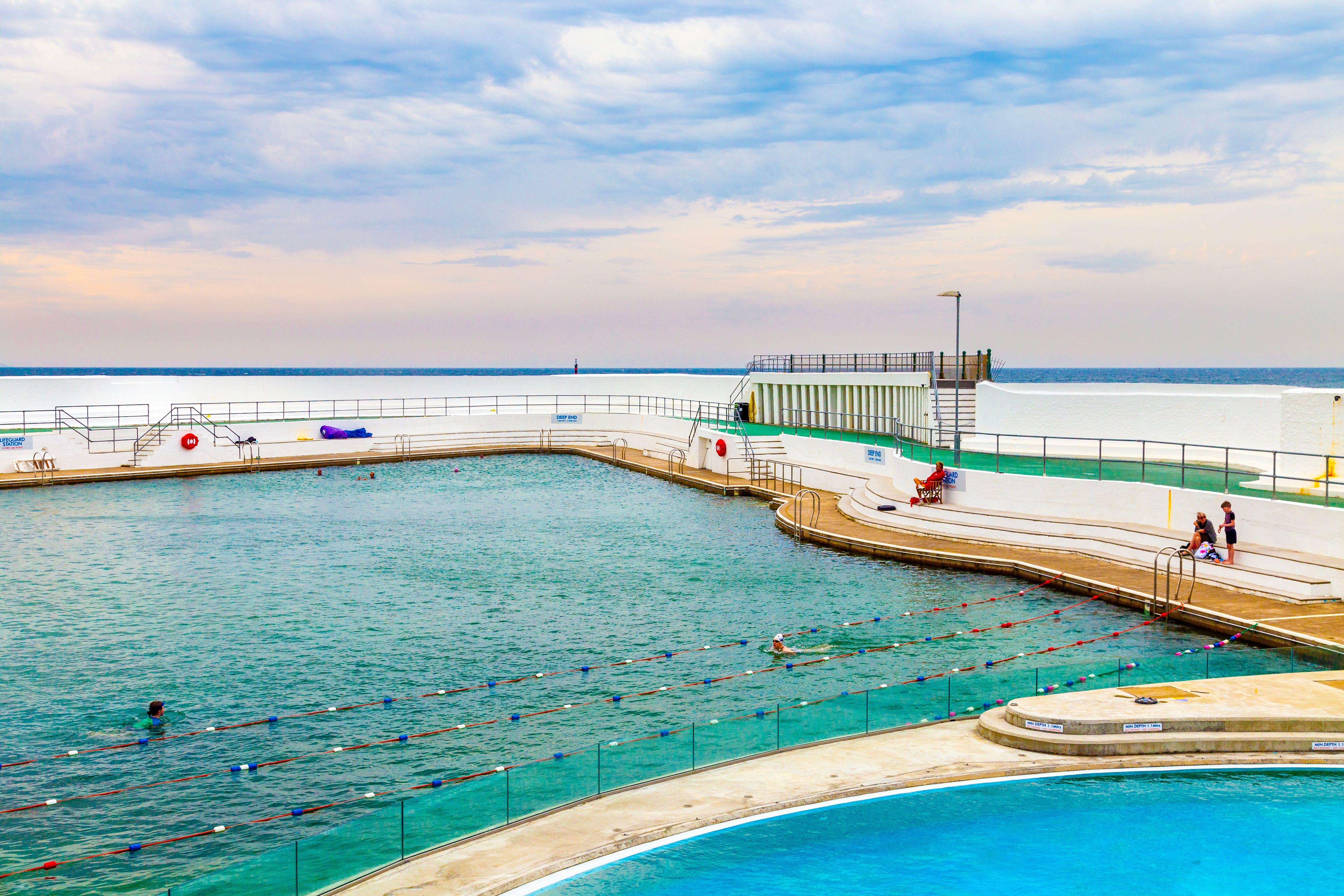 People swim in the art deco lido Jubilee Pool overlooking Mounts Bay, Penzance, Cornwall