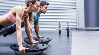 Man and women performing push-ups on balance trainers side by side