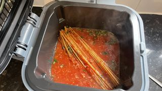 Uncooked spaghetti, chopped tomatoes and basil in the Ninja Speedi's cooking pot
