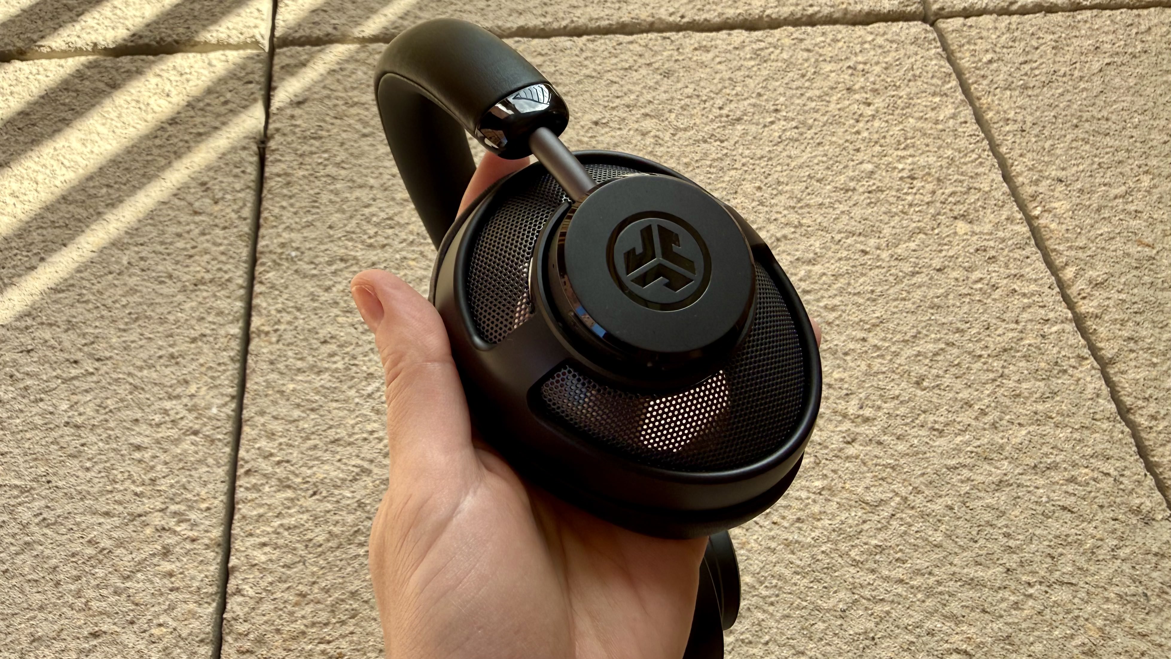 The jlab jbuds open wireless headphones pictured on a stone surface