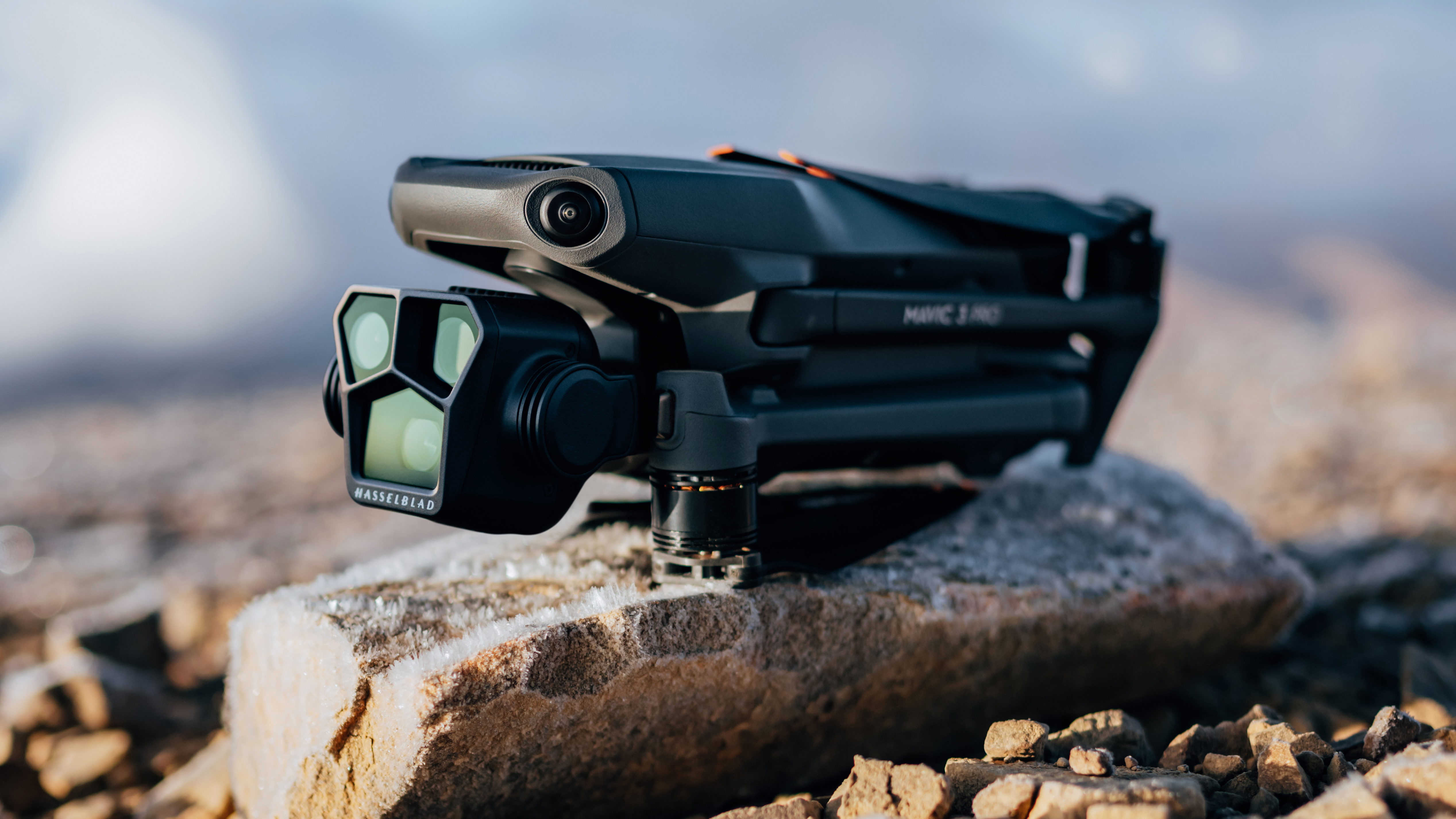 A folded DJI Mavic 3 Pro drone sitting on a rock on the beach