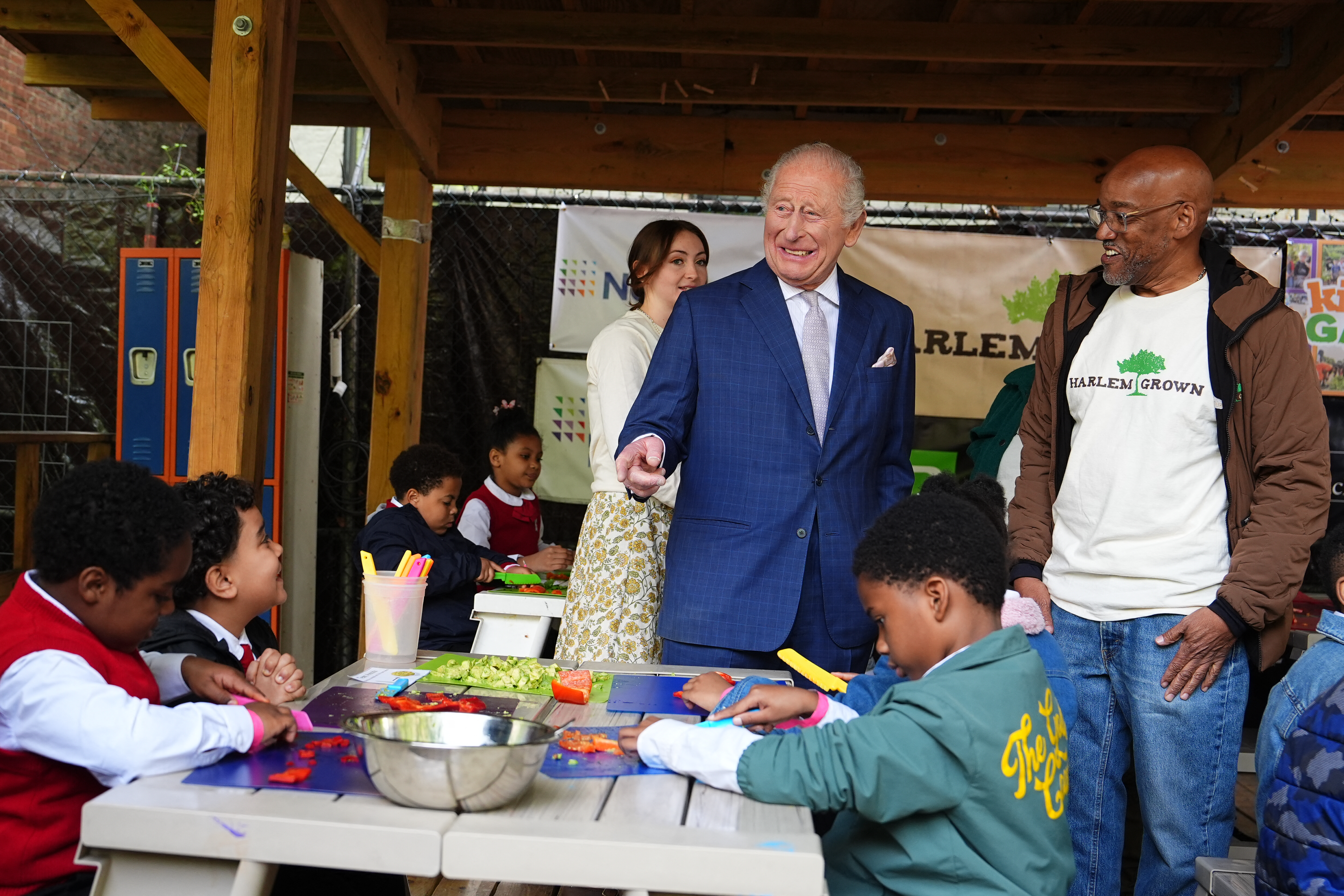 King Charles smiling in a blue suit talking to students