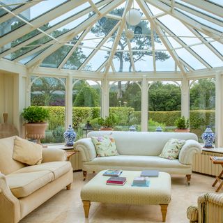 garden view sitout area with white sofa and glass top roof