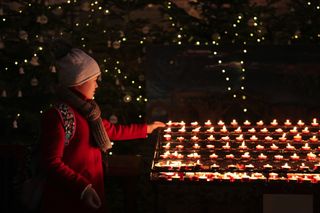 A young girl lighting a candle in a Church during Christmas time.