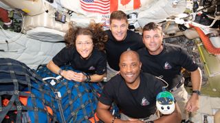 art002e013365 (April 7, 2026) – The Artemis II crew – (clockwise from left) Mission Specialist Christina Koch, Mission Specialist Jeremy Hansen, Commander Reid Wiseman, and Pilot Victor Glover – pause for a group photo with their zero gravity indicator "Rise," inside the Orion spacecraft on their way home. Following a swing around the far side of the Moon on April 6, 2026, the crew exited the lunar sphere of influence (the point at which the Moon's gravity has a stronger pull on Orion than the Earth's) on April 7, and are headed back to Earth for a splashdown in the Pacific Ocean on April 10.