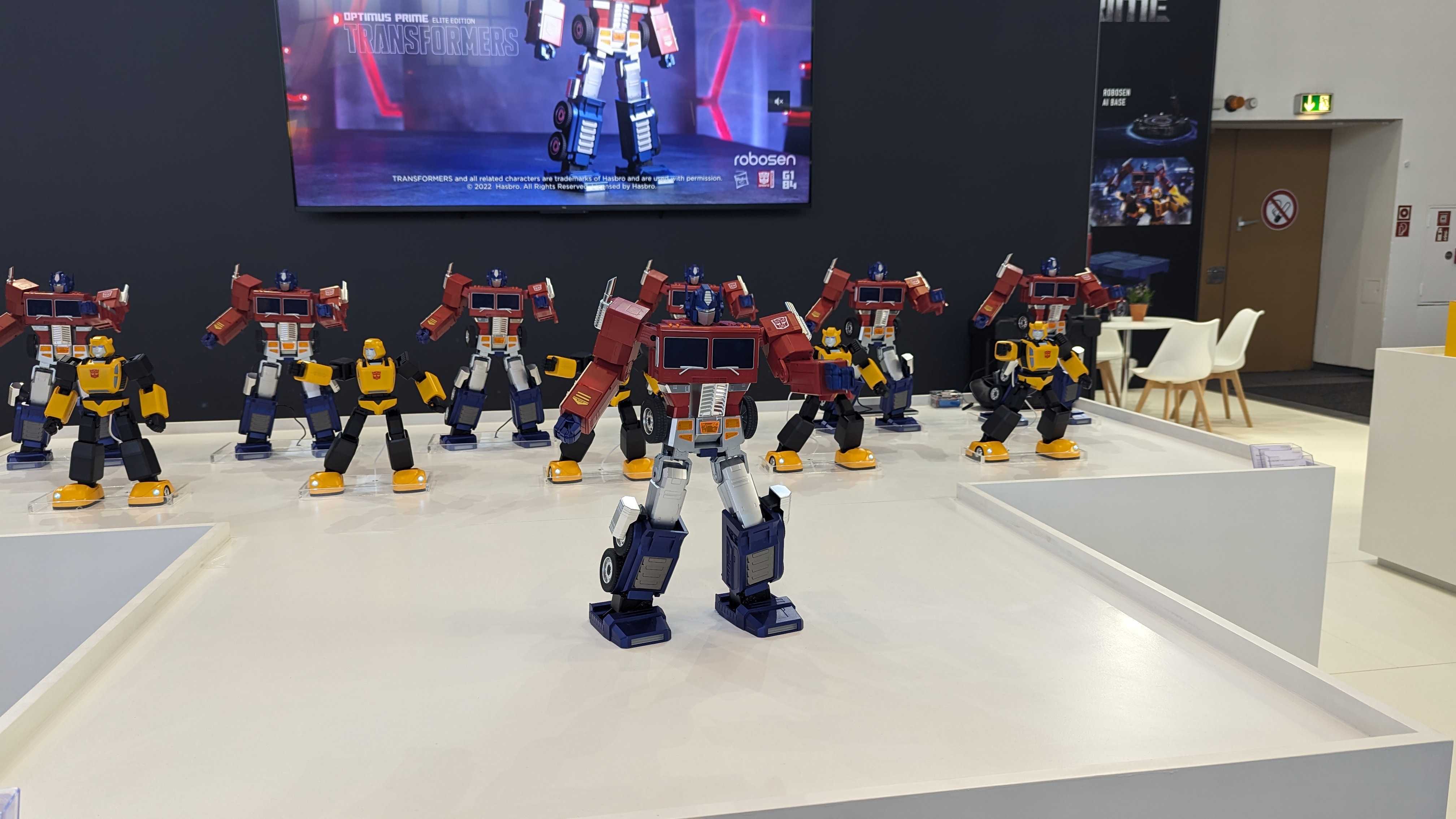 Several Optimus Primes and Bumblebees dancing on a white table