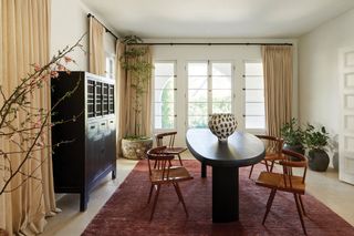 European style dining room with maroon carpet, curtains and round black dining table